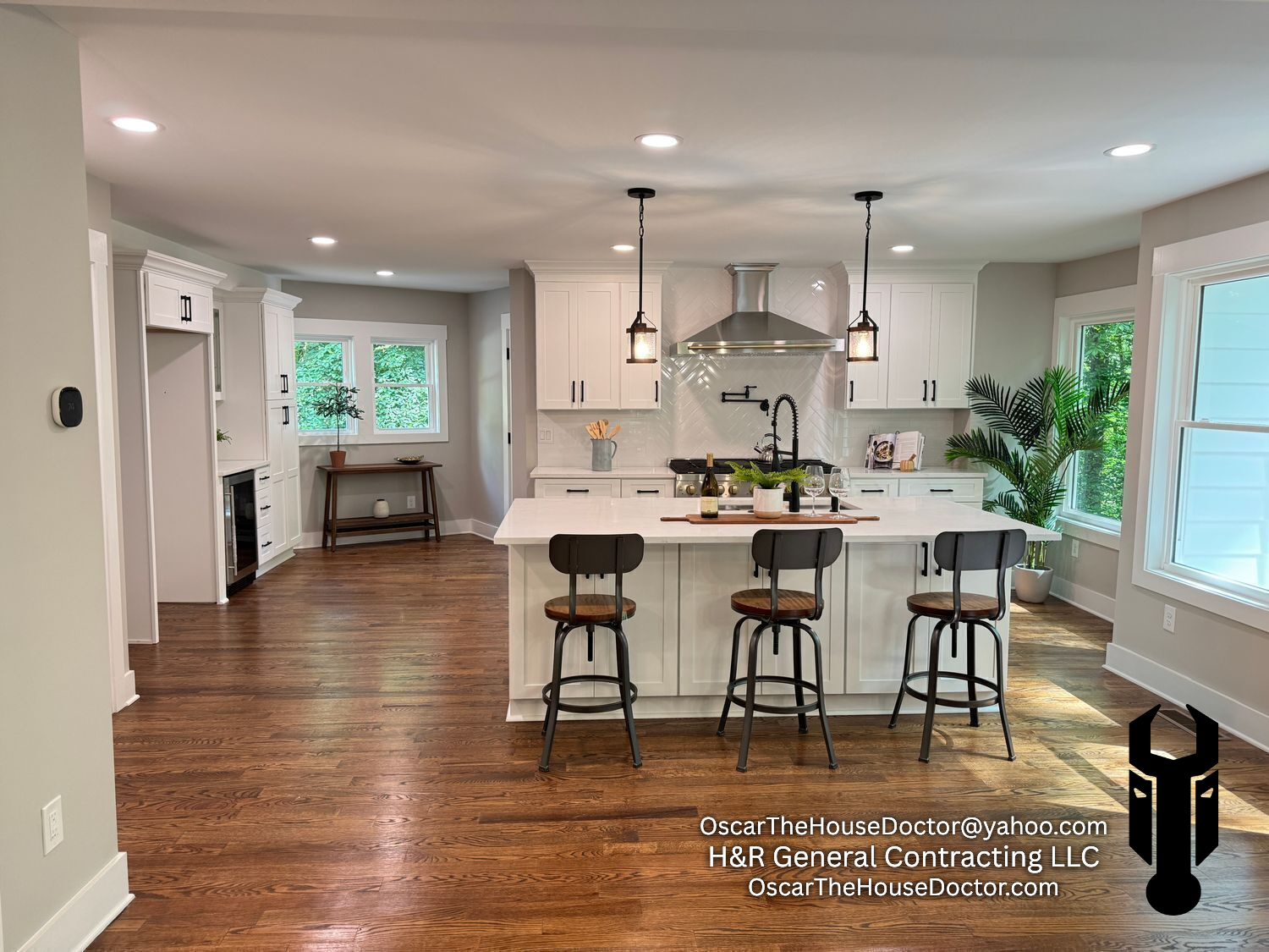 Open-concept kitchen renovation with real wood flooring, new cabinets and kitchen island, countertops, and lighting.